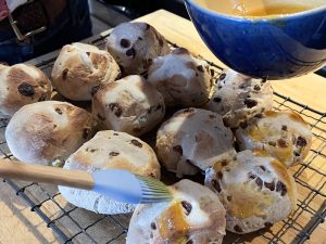 Hot cross buns being glazed with syrup